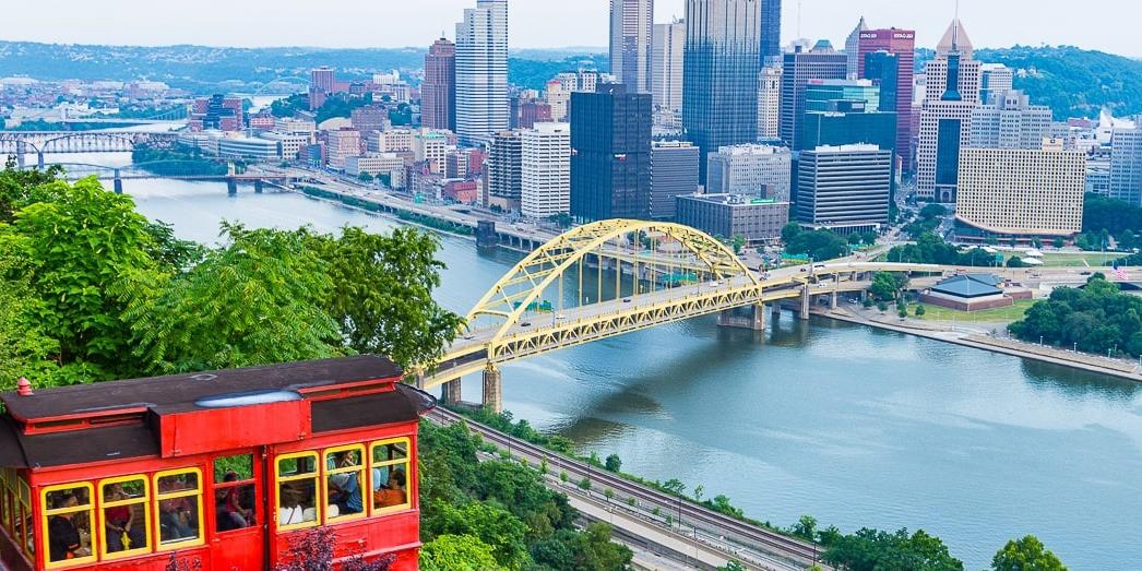 Photo of 匹兹堡's red incline car framing the city's skyline in the distance. 